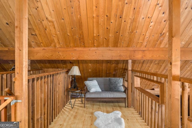 living area with wooden walls, beam ceiling, wood ceiling, and hardwood / wood-style flooring