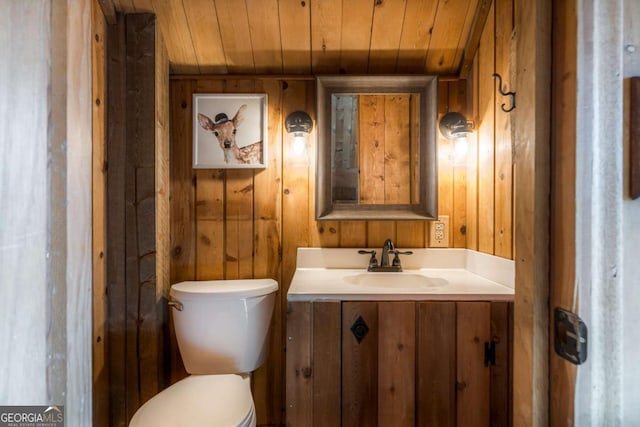 bathroom featuring vanity, wooden walls, toilet, and wood ceiling