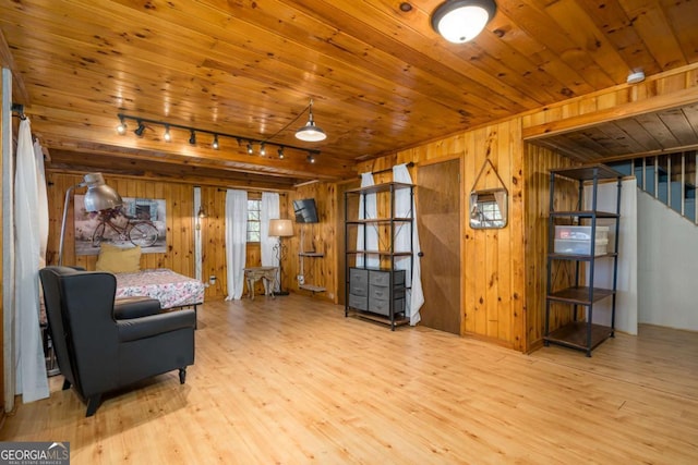 living area with wooden walls, wood finished floors, wooden ceiling, and stairway