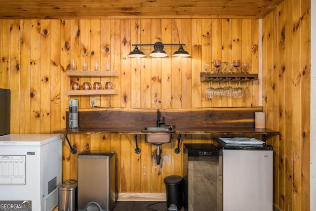 kitchen with a sink, refrigerator, and wood walls