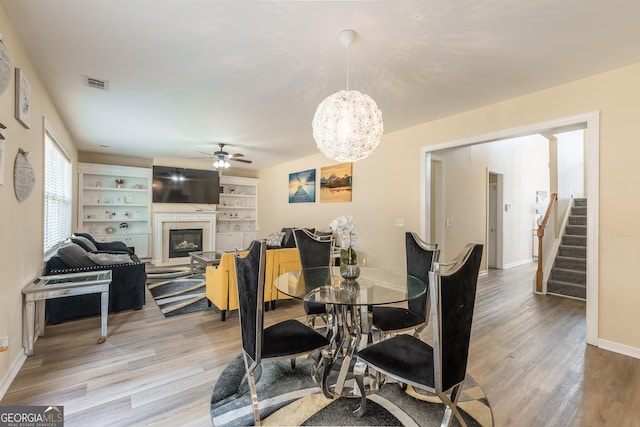 3450 Long Lake Dr, Douglasville, GA 30135 - dining space with visible vents, light wood-type flooring, ceiling fan with notable chandelier, stairs, and a glass covered fireplace