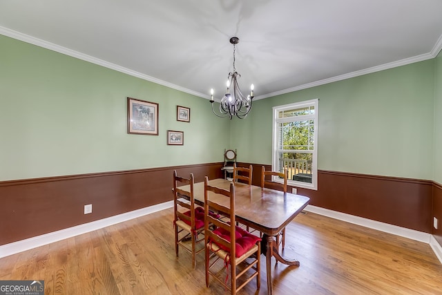 dining space with a chandelier, wood finished floors, baseboards, and ornamental molding