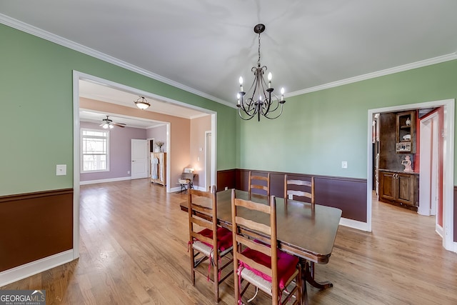 dining space with baseboards, an inviting chandelier, crown molding, and light wood-type flooring