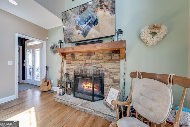 living area featuring baseboards, wood finished floors, a fireplace, and crown molding