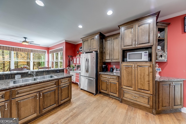 kitchen featuring a sink, freestanding refrigerator, light wood-type flooring, crown molding, and white microwave