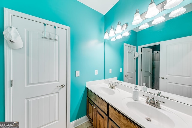 full bath with baseboards, a sink, and double vanity