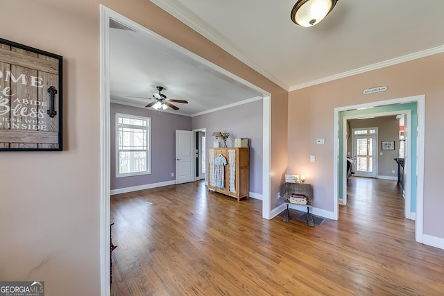 living area featuring baseboards, a ceiling fan, wood finished floors, and ornamental molding