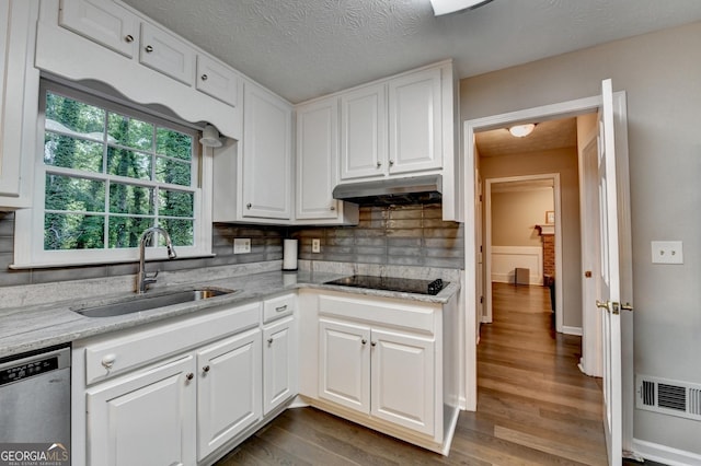 kitchen featuring stainless steel dishwasher, under cabinet range hood, a sink, black electric cooktop, and white cabinets