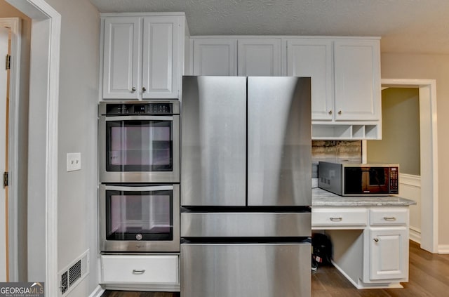 kitchen featuring white cabinetry, stainless steel appliances, and visible vents