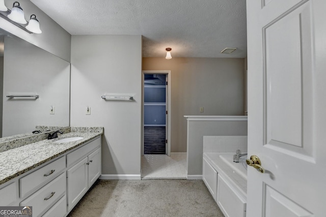 full bath featuring a garden tub, a textured ceiling, baseboards, and vanity