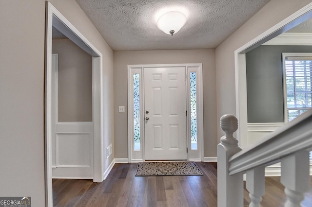 foyer with a textured ceiling, baseboards, and dark wood-style floors