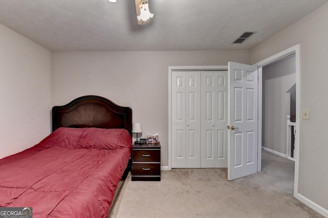 bedroom featuring baseboards, light carpet, a closet, and visible vents