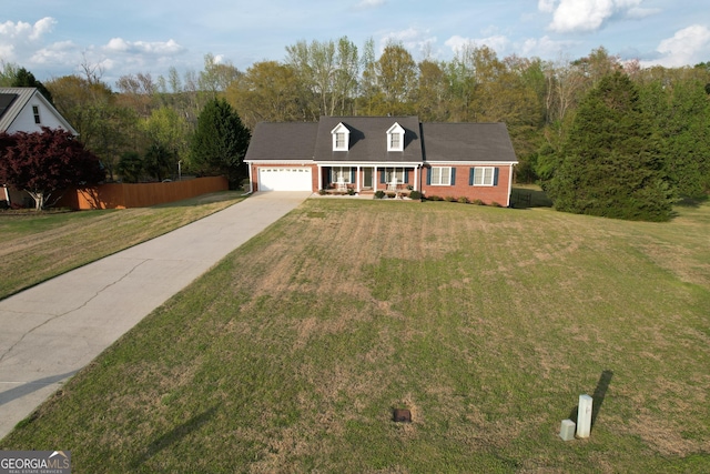 cape cod house with a front lawn, an attached garage, brick siding, and concrete driveway