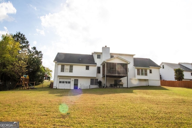 rear view of property with a chimney, a sunroom, a lawn, a garage, and a playground
