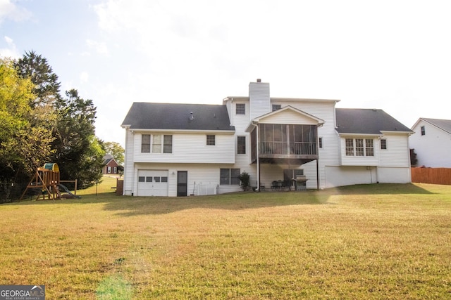 rear view of house featuring a chimney, a sunroom, a playground, a garage, and a lawn