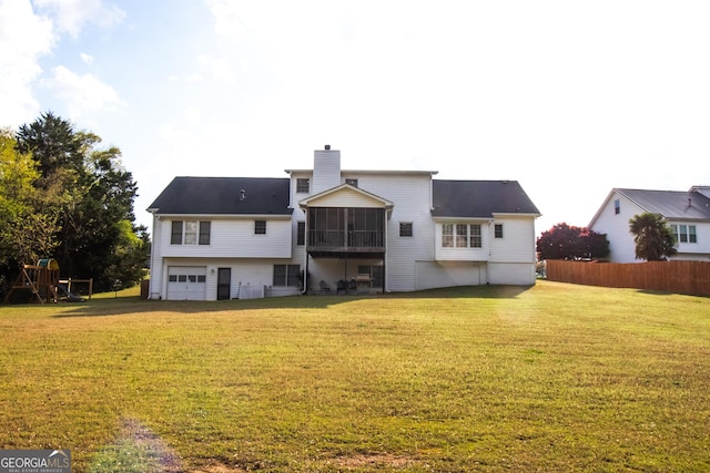 rear view of house featuring a chimney, a sunroom, a yard, and an attached garage