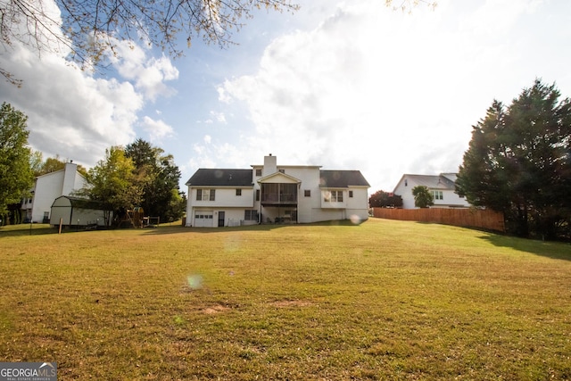 rear view of house featuring fence and a yard