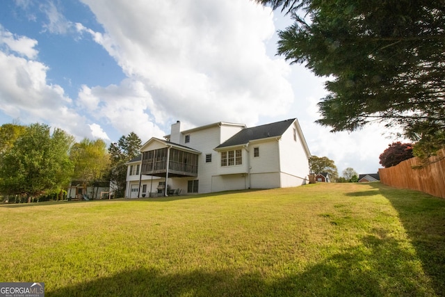 back of house featuring a sunroom and a lawn