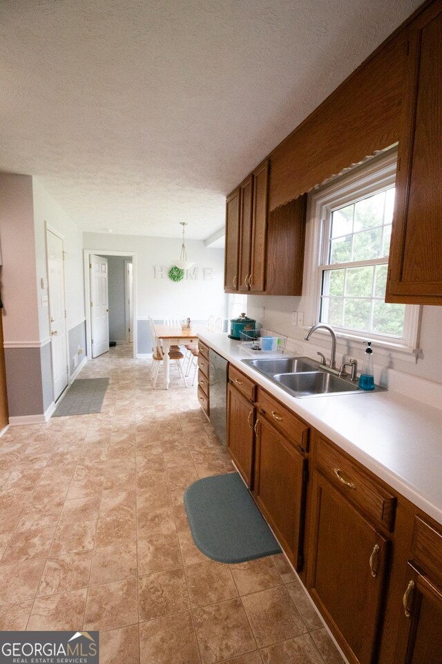 kitchen with light countertops, a sink, brown cabinets, and dishwasher