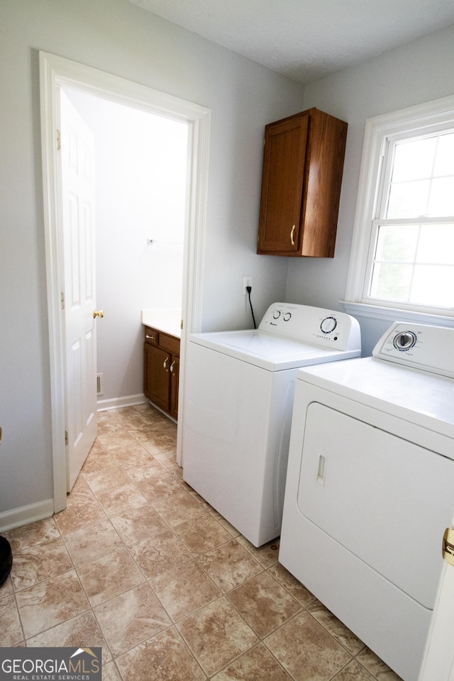 washroom with washing machine and clothes dryer, cabinet space, and baseboards