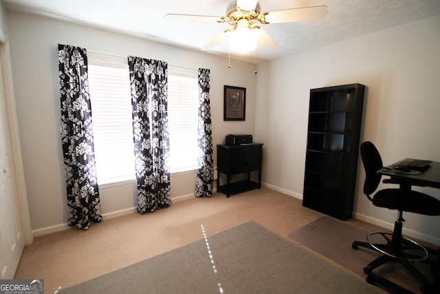 carpeted office with baseboards and a ceiling fan