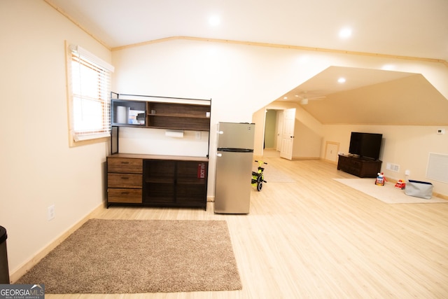 interior space featuring freestanding refrigerator, wood finished floors, lofted ceiling, baseboards, and visible vents