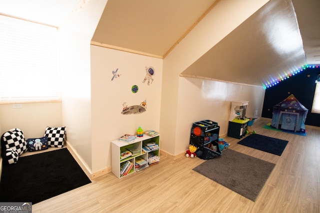 recreation room with baseboards, lofted ceiling, and wood finished floors