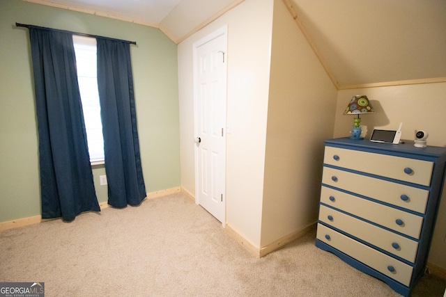 bedroom with light colored carpet, baseboards, and vaulted ceiling
