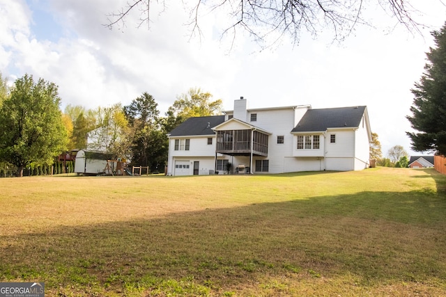 rear view of house with an attached garage, a chimney, a yard, and an outbuilding