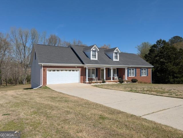 new england style home with an attached garage, concrete driveway, a front yard, brick siding, and a porch