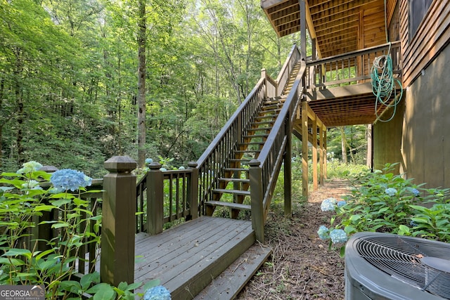 wooden deck featuring a wooded view, stairway, and central air condition unit