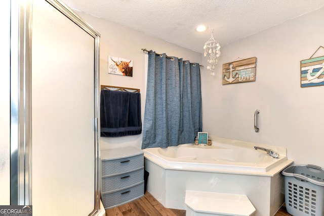 181 King St, Clermont, GA 30527 - full bathroom with wood finished floors, a textured ceiling, and a bath