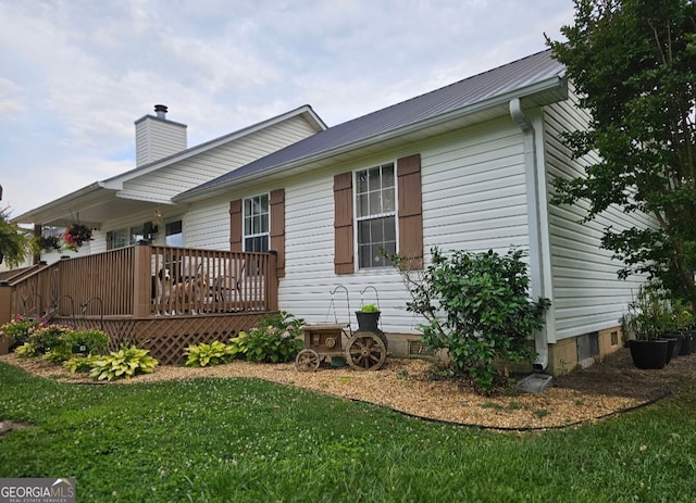 view of home's exterior with a lawn, a chimney, a wooden deck, and crawl space