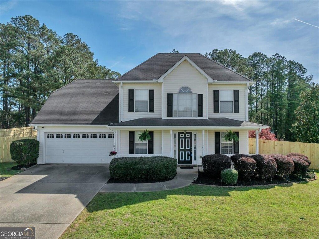 view of front of property featuring an attached garage, fence, concrete driveway, and a front yard