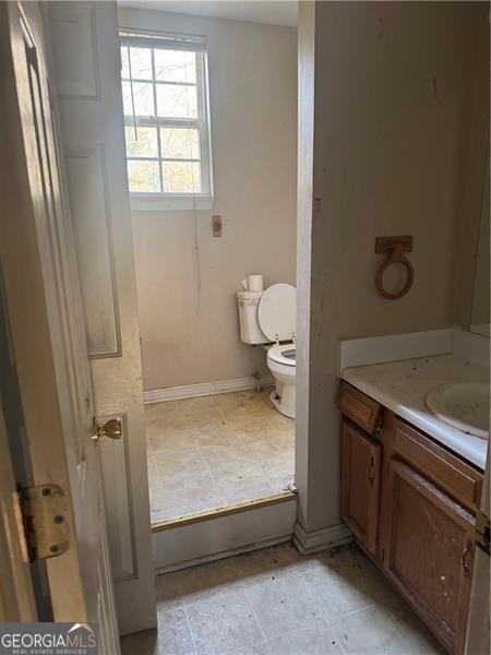 bathroom featuring baseboards, toilet, and vanity