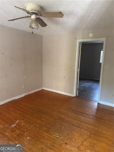 spare room with hardwood / wood-style floors, a ceiling fan, and baseboards