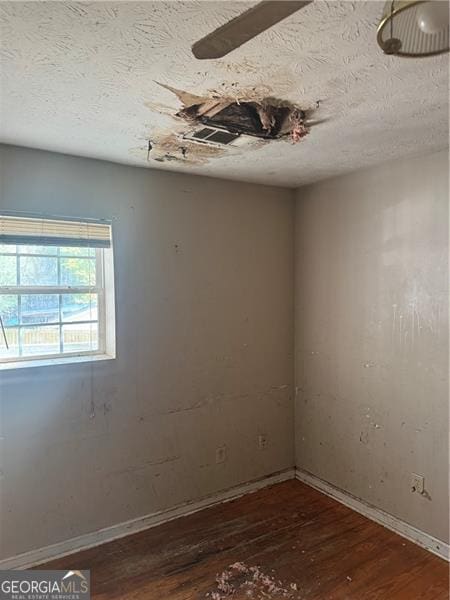 empty room with baseboards, wood finished floors, and a textured ceiling
