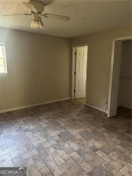 empty room featuring baseboards and ceiling fan