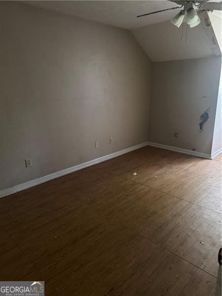 unfurnished room with baseboards, vaulted ceiling, ceiling fan, and dark wood-type flooring