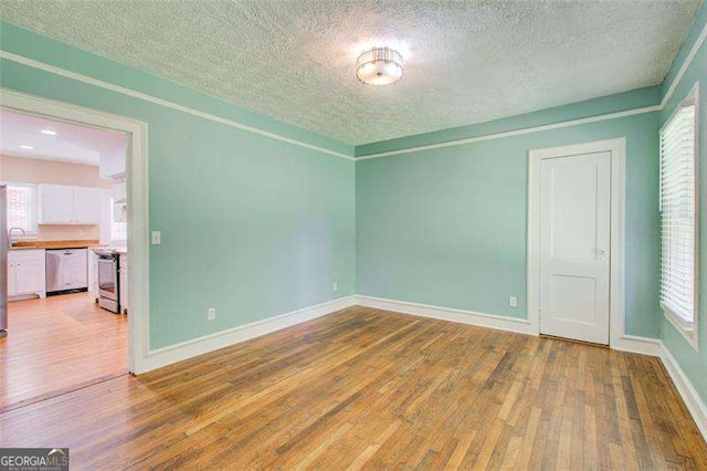 unfurnished room featuring wood-type flooring, baseboards, and a textured ceiling