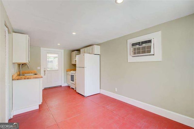 kitchen with recessed lighting, white appliances, baseboards, a sink, and white cabinets