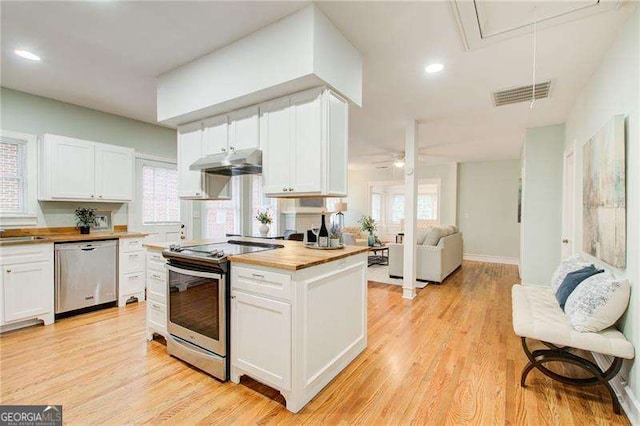 kitchen featuring visible vents, wooden counters, appliances with stainless steel finishes, under cabinet range hood, and white cabinetry