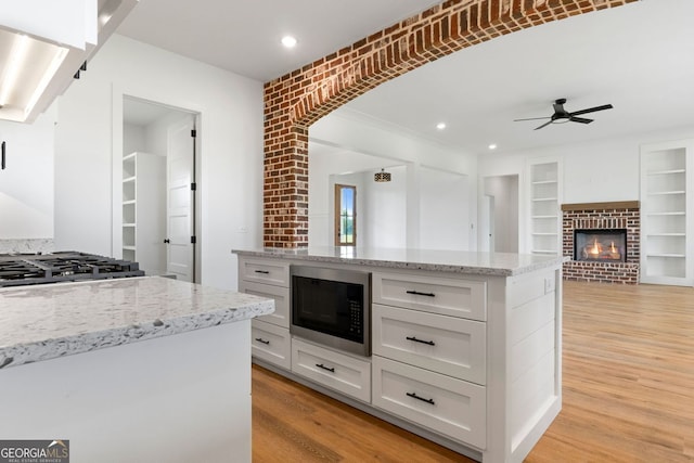 284 Community House Rd, Barnesville, GA 30204 - kitchen featuring stainless steel microwave, ceiling fan, white cabinetry, light wood-style flooring, and light stone countertops