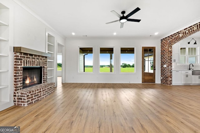 284 Community House Rd, Barnesville, GA 30204 - unfurnished living room featuring a ceiling fan, healthy amount of natural light, ornamental molding, light wood-style floors, and a fireplace