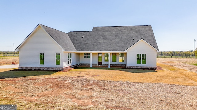 rear view of house featuring fence and a shingled roof