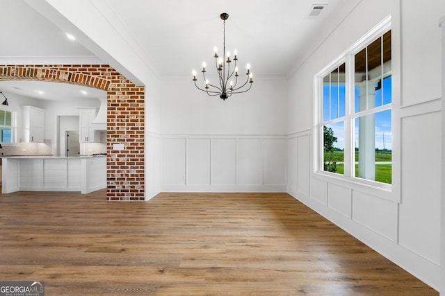 284 Community House Rd, Barnesville, GA 30204 - unfurnished dining area featuring a decorative wall, a chandelier, light wood-style flooring, wainscoting, and crown molding