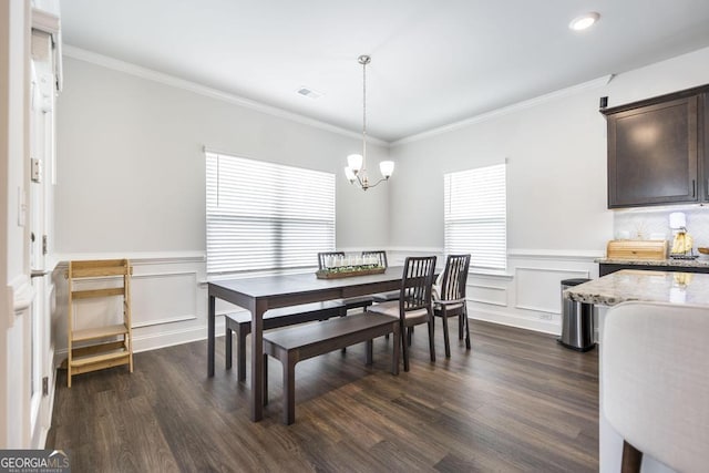 dining space with an inviting chandelier, ornamental molding, visible vents, a wainscoted wall, and dark wood-style flooring