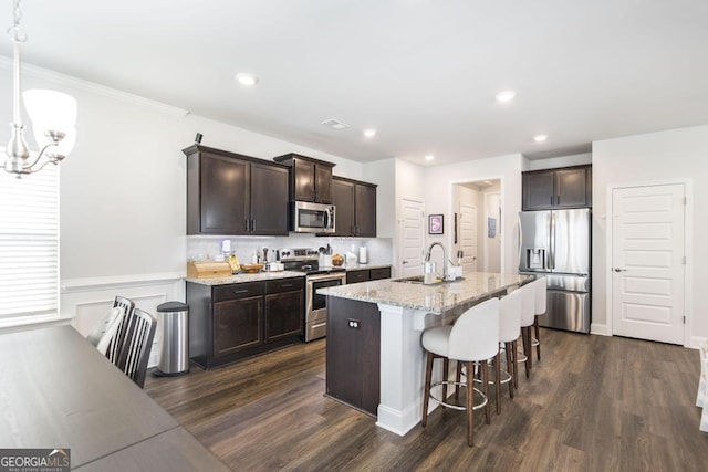 kitchen featuring a notable chandelier, a kitchen breakfast bar, dark brown cabinets, appliances with stainless steel finishes, and a sink