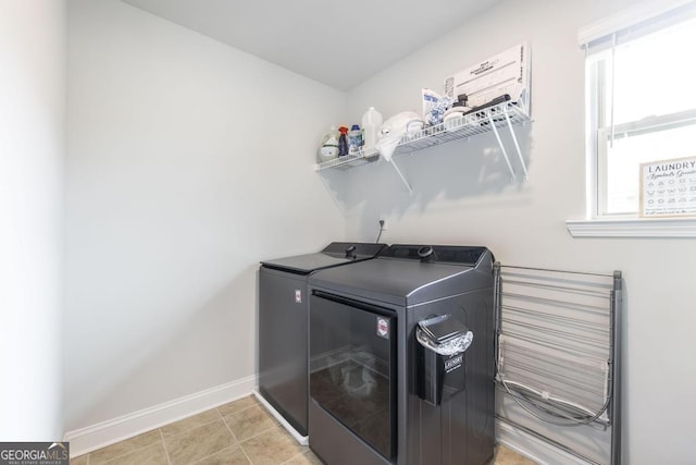 clothes washing area featuring laundry area, washing machine and clothes dryer, baseboards, and light tile patterned floors