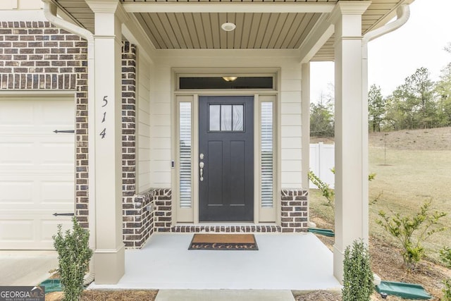 view of exterior entry with an attached garage and stone siding